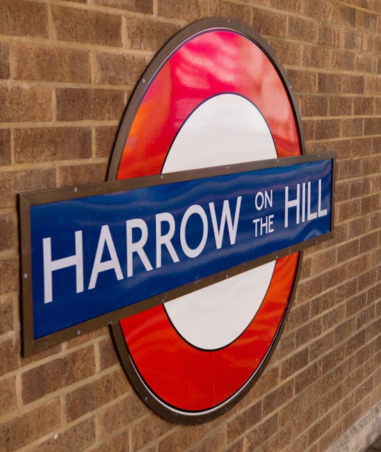 A round London Underground style station sign mounted on a brick wall displaying 'Harrow on the Hill' in white capital letters on a blue background, with a red and white circular symbol behind it. The sign is positioned at a slight angle, illustrating a typical entrance or exit point within the Herne Hill area. The brick wall features evenly spaced, reddish-brown bricks with subtle mortar lines surrounding the sign, and the lighting appears natural and even, highlighting the signage's clarity and the texture of the brick surface. This visual aligns with the context of relocation services in the Herne Hill area, suggesting transportation or travel infrastructure relevant to house removals and furniture transport operations performed by professional movers such as Man with Van Herne Hill.